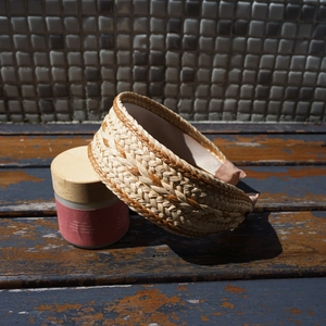 Detail of woven raffia headband in beige and gold brown on a vintage wooden bench