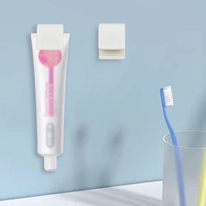 Wall-mounted white plastic clip for toothpaste and facial cleanser on a blue bathroom wall