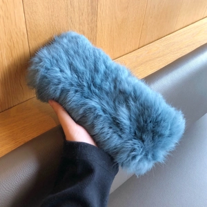 Detail der flauschigen Textur des blauen Kaninchenfell-Stirnbands in der Hand gehalten