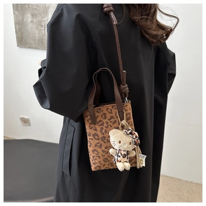 Detail of leopard print suede crossbody bag featuring a cute plush kitten charm
