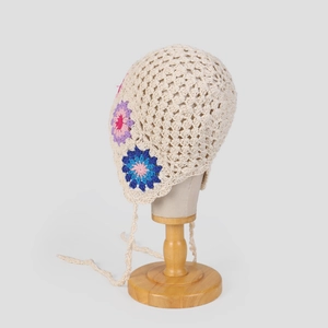 Detailed macro view of handcrafted crochet bonnet with colorful floral patterns and thin ties
