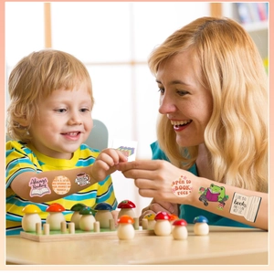 Close-up of children applying colorful reading-themed temporary tattoos on an arm