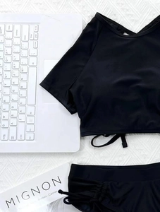 Flat lay of black two-piece bikini featuring drawstring swim bottoms and short sleeve top