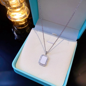 Macro view of silver geometric pendant with white shell inlay and halo crystals