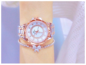 Close-up of women's dual-tone rhinestone watch and sparkling bow bracelet on wrist