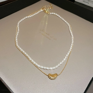 Détail du pendentif haricot doré avec collier de perles et chaîne serpent lisse