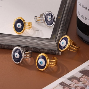 Five gold and silver Evil Eye open rings with blue enamel on a decorative book background