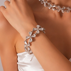Close-up of a silver flower necklace with clear teardrop crystals on a female model
