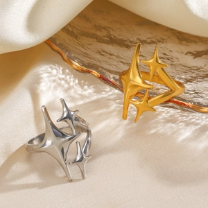 Minimalist stainless steel open star rings in gold and silver finishes on satin tray
