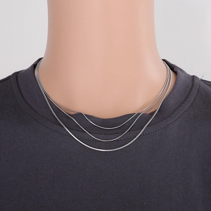 Close-up of triple-layered silver snake chain necklace on a minimalist model