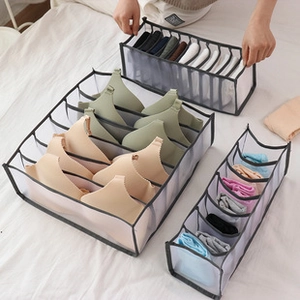 Three-piece black mesh drawer organizers for bras, socks and underwear shown on a bed