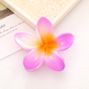 Macro detail of the gradient pink and yellow plumeria hair claw clip on a white surface