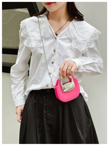 Close-up of mini pink bag with silver metal handle and chain strap held by a model