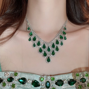 Close-up of silver tassel necklace with green water-drop gems and sparkling rhinestones