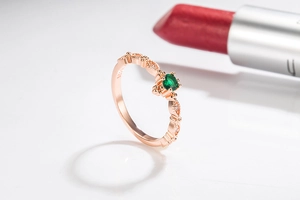 Detailed close-up of rose gold ring with green emerald stone and 925 silver hallmark