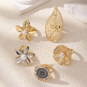 Macro detail of 5-piece gold ring set featuring pearls, floral petals and leaf motifs