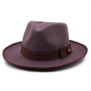 Detail of dark purple wool fedora hat with brown ribbon and gold buckle accent