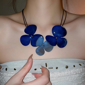 Detail shot of oversized blue resin flower pendants on a black cord choker necklace