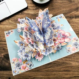 Carte de vœux pop-up 3D avec un grand papillon bleu et des fleurs colorées et enveloppe