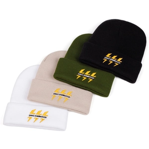 Détail de quatre bonnets en tricot d'hiver en blanc, beige, vert et noir brodés