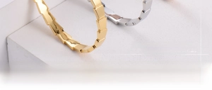 Macro shot of gold and silver snake-scale textured bracelets on a white stone base
