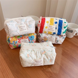 Detailed stack of quilted cotton floral and bear print cosmetic pouches with zipper
