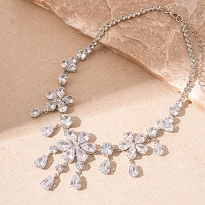 Macro detail of silver flower necklace with zircon teardrop pendant on stone surface