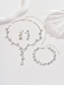 Detail view of a silver rhinestone jewelry set with necklace earrings and bracelet on silk