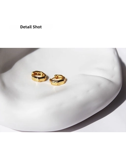 Detail shot of gold-plated bamboo texture hoop earrings on white ceramic tray
