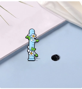 Detailed close-up of a blue chemical test tube enamel pin with white flowers and green leaves