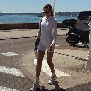 Close-up of white long-sleeve romper featuring a zipper collar and contouring waist seams