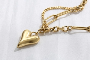 Dettaglio della collana con ciondolo a cuore dorato e catena a maglie miste rifinita