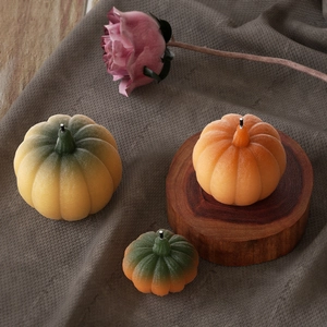 Detailed close-up of textured pumpkin candles in orange and yellow on a wooden coaster