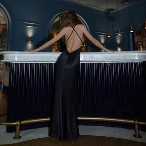 Détail des bretelles croisées sur une robe de soirée en satin noir avec dos nu soyeux
