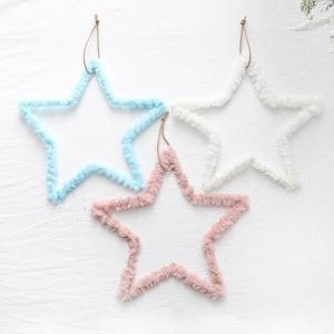 Plush star Christmas tree ornaments in blue, pink and white on a soft textured background