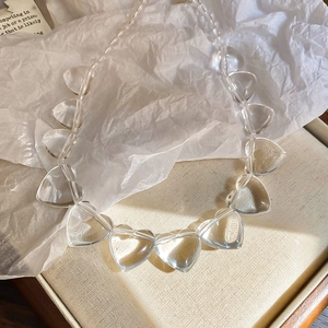 Macro shot of irregular transparent acrylic heart beads on a minimalist choker necklace