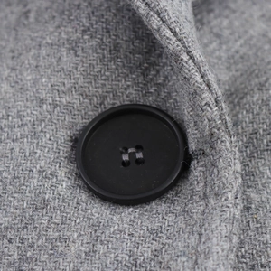 Close-up of a classic black four-hole button on textured grey wool coat fabric