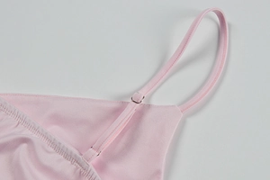 Detail of adjustable silver metal buckle and silk shoulder strap on pink dress