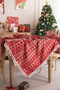 Detail of red Christmas tablecloth with reindeer jacquard patterns and white fringe edge
