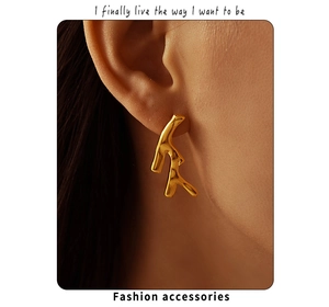 Close-up of gold PVD plated stainless steel irregular branch earrings on a model ear