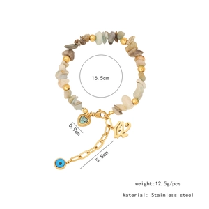 Detail of natural stone heart and evil eye charms on stainless steel bracelet