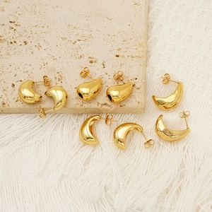 Boucles d'oreilles goutte dorées minimalistes au fini poli sur une surface en pierre naturelle