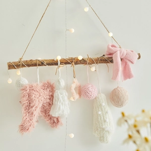 Christmas hanging decorations with pink knit plush ornaments and warm lights on a branch