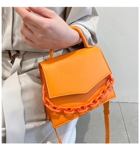 Detail of bright orange square handbag with thick chain strap and smooth PU leather
