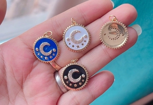 Detail of celestial coin charms featuring moon and star motifs in blue, white, and black enamel