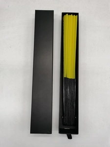 Detail view of a yellow folding fan with black bamboo ribs in a minimalist gift box