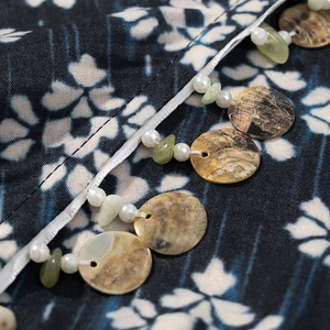 Détail macro du tissu imprimé géométrique avec pendentifs en coquillage et franges