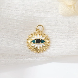Close-up of golden evil eye pendant with white enamel and blue iris on textured fabric