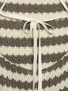 Dettaglio del tessuto a maglia zigzag con filo dorato e laccio a fiocco bianco