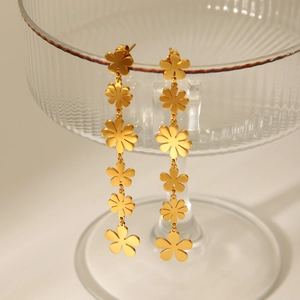 Close-up of 18k gold-plated daisy flower drop earrings hanging on a glass cup